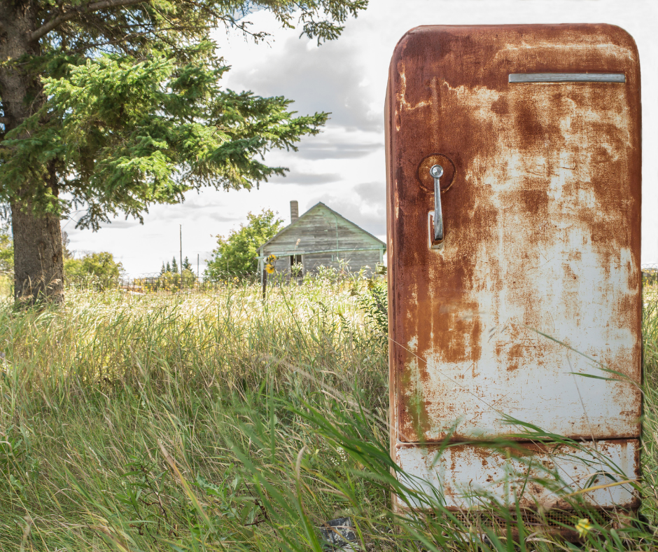 Old and rusty fridge on a grassy field Old and rusty fridge on a grassy field