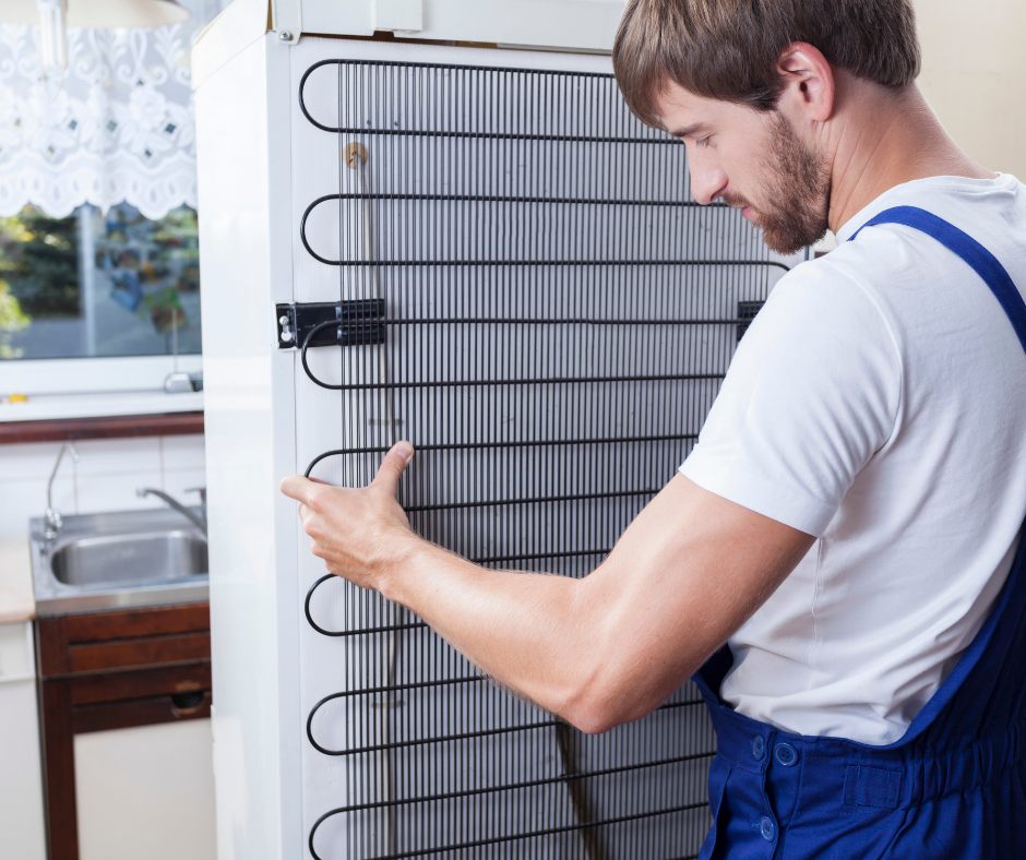 Man removing the coil from the back of a fridge Man removing the coil from the back of a fridge