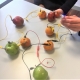 Picture of fruit circuit activity on a table, wires, fruit, zinc, .copper and LEDs, child holding it