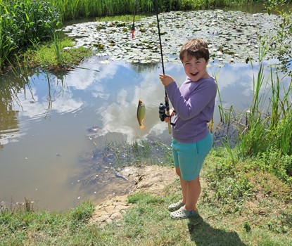 Arlo A picture of Arlo, an 8 year old boy, fishing by a pond. The photo shows the fish on the line he caught