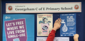 Georgeham Children's hand holding up a poster saying "We are a Refill School" at Georgeham C of E Primary school.