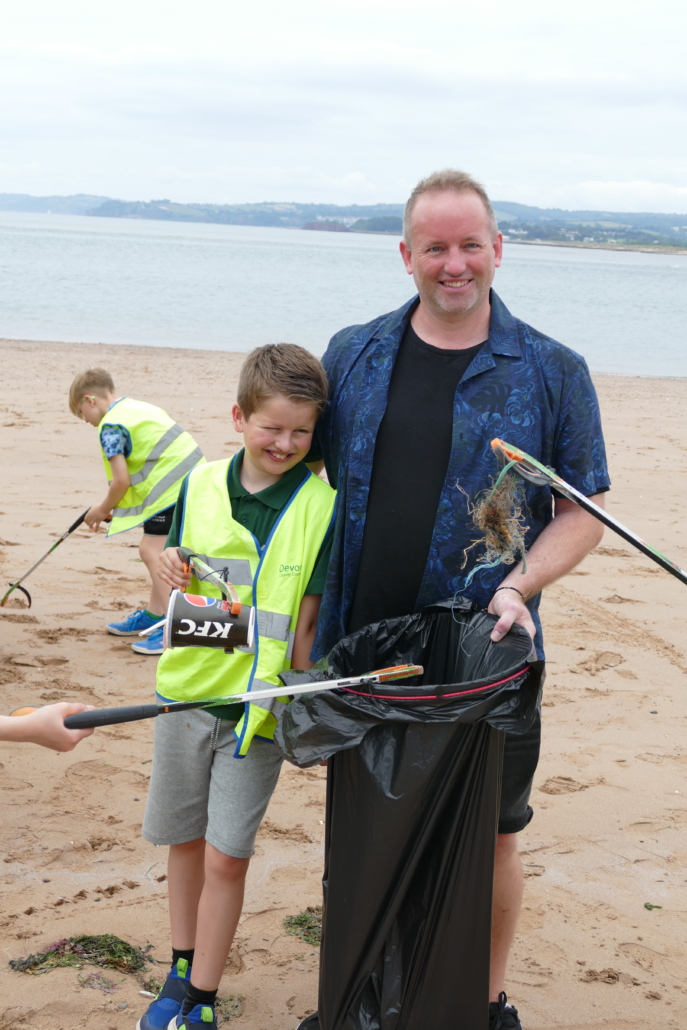 Dad and son at litter picking. A dad and his son smile for the camera while litter picking.