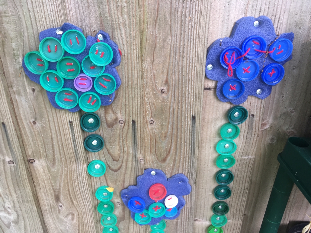 IMG_1534 flower sculpture on wall made from repurposed milk bottle tops at Holsworthy Primary School