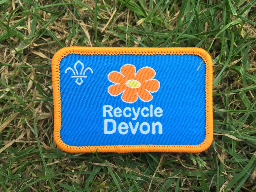 Recycle Devon Scout Badge (old logo) on grassy background Close up of a Recycle Devon Scout Badge lying on grass