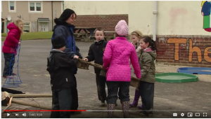 Loose Parts YouTube Video Still from video of children in coats playing outdoors with adult play supervisor