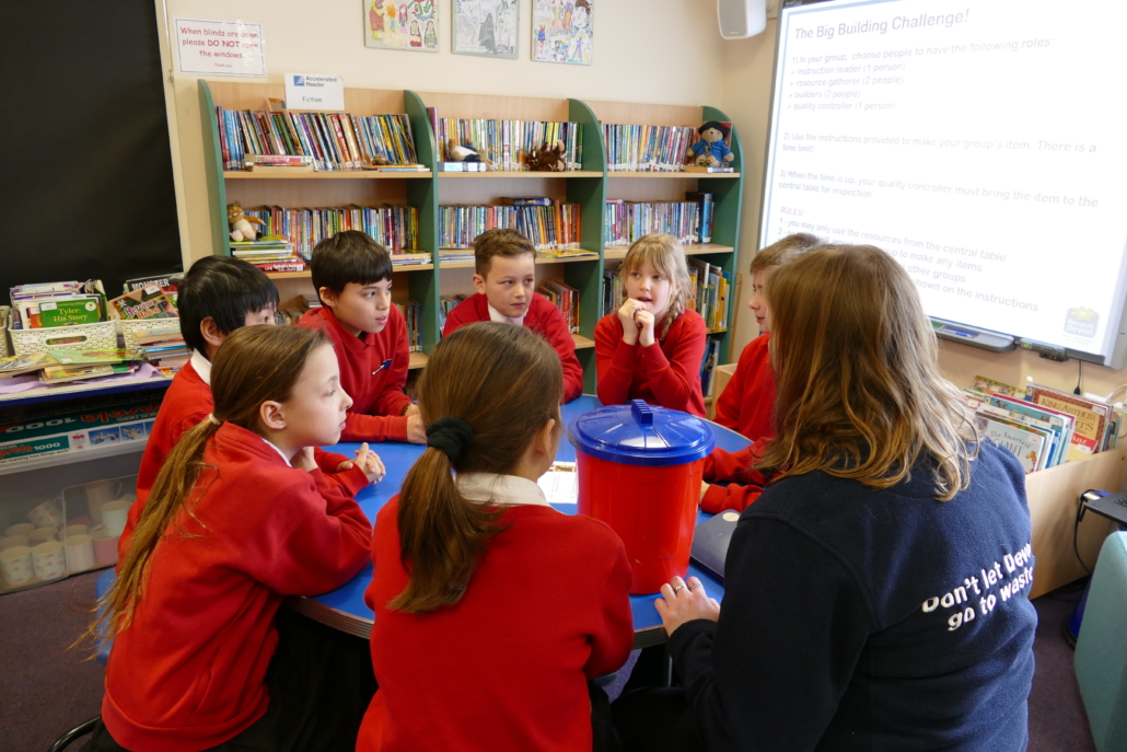 Active student participation from Totnes schoolchildren Children sitting round a table, dressed in school uniform with an adult wearing a Don't Let Devon go to Waste top