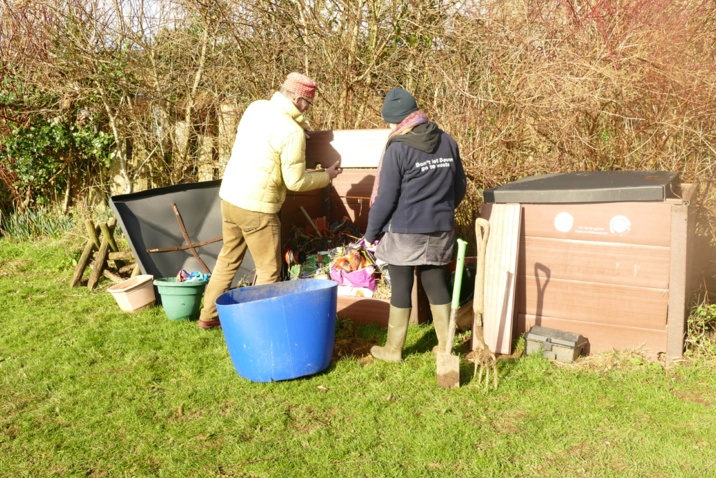 Finding the bins was a start! Two adults look inside a compost bin