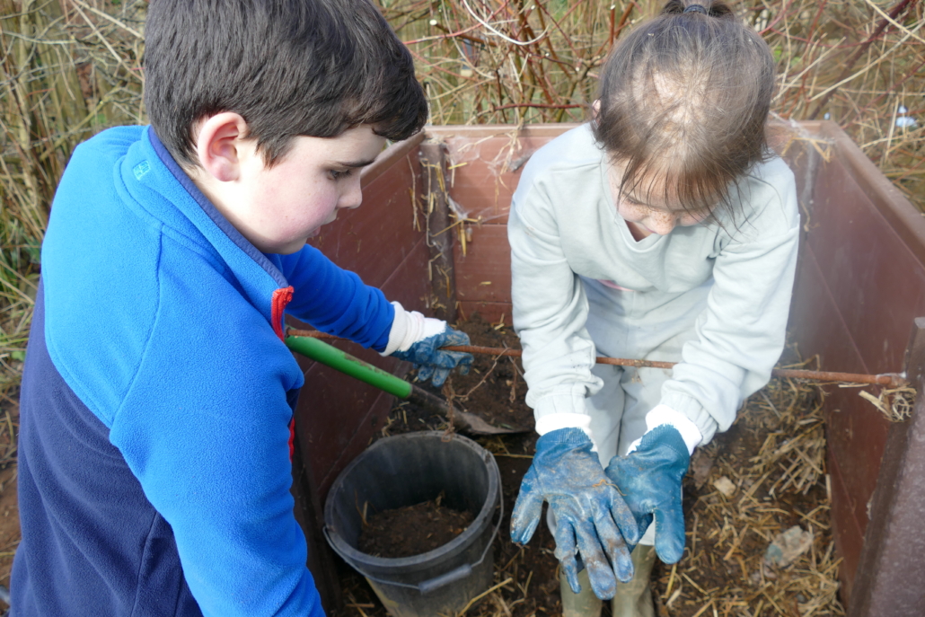 Jobs included moving compost Two childre wearing gloves, one shows the other a bug found in compost