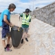 Adult and male children collecting litter on a beach with litter picker and bin bag