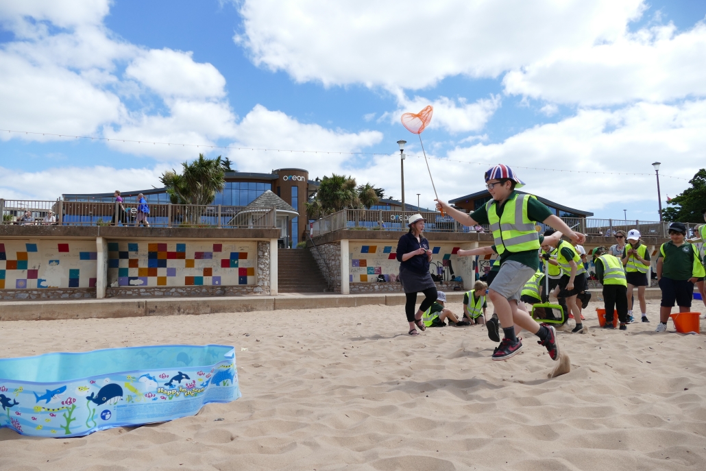 Child running on a beach with a net in the air