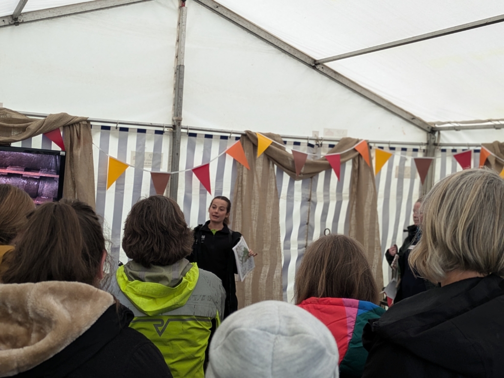 A photo a presenter from the National Trust giving a presentation to an audience outside in a tent