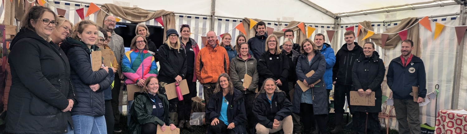 A group of people that attended teacher training, having a picture taken outside in a tent