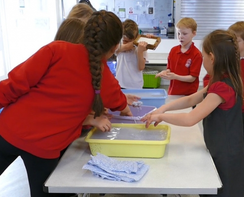 Children using trays of newspaper and water to make new paper