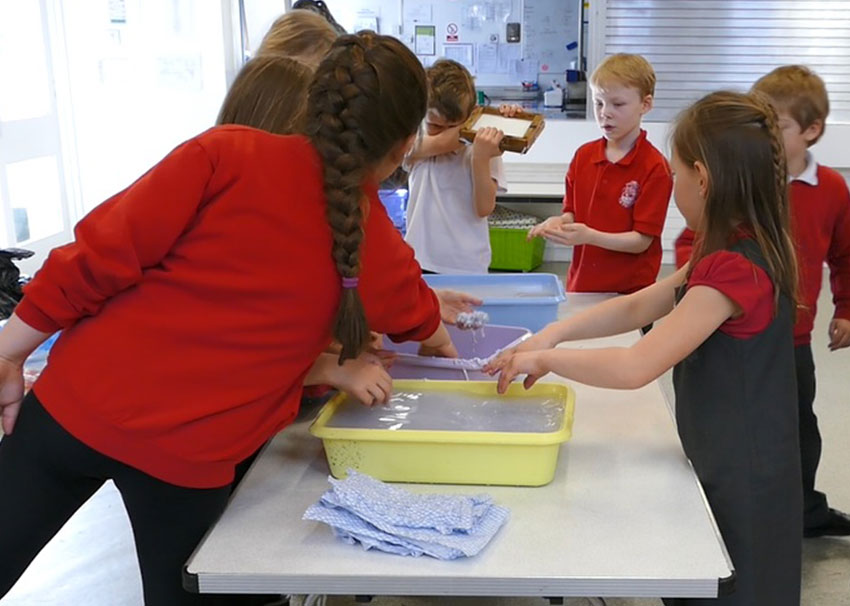 Papermaking Children using trays of newspaper and water to make new paper