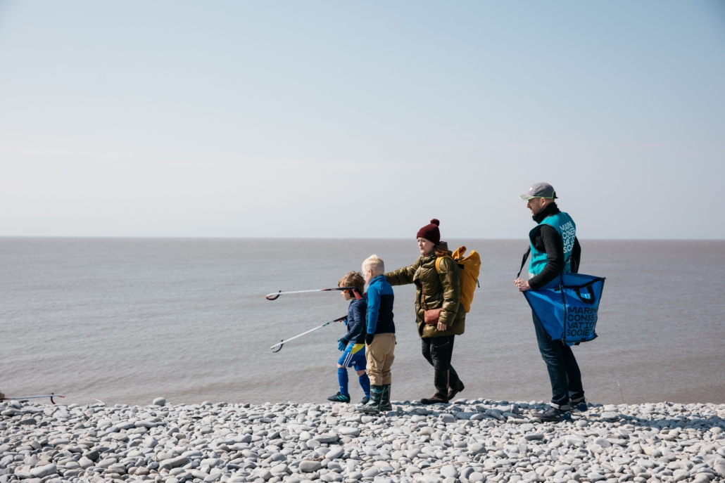 Image of a family of fours at the beach, picking up litter. Part of the sustainability bulletin