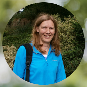 Trish, who works at Devon County Council, is in a blue jumper in outdoor woodland