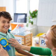 Teaching putting a badge on a child to reward them for their environmental efforts. It is the main picture for the Universal Children's Day post. This is a stock photo.