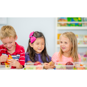 Three children smiling while having a packed lunch