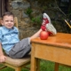 Child sitting outside at desk with legs on desk with apple and pencils