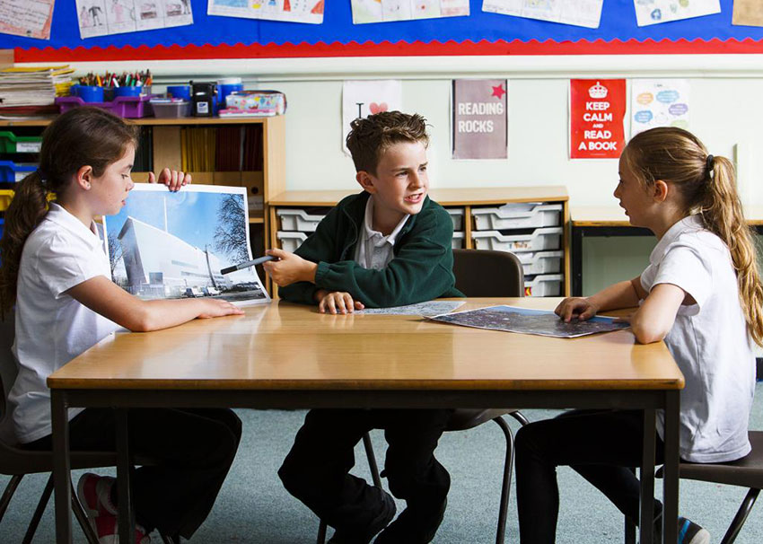 3 children around a table with poster of Exeter EfW discussing