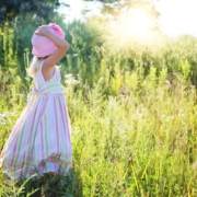 Sustainability Bulletin title picture of a little girl in a long dress bathed in summer sunshine standing with her back towards us in a field