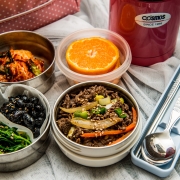 Photo showing a range of foods in lunchboxes and reusable tubs; cutlery in a pot and