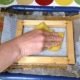 Picture of someone pressing down on recycled paper making frame