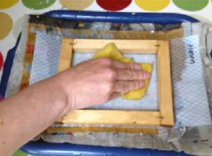 Picture of someone pressing down on recycled paper making frame