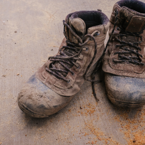 Muddy work boots on a concrete floor outside