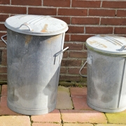 Two simple metal dustbins on a patio.
