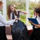 3 secondary age students weighing a rubbish bag using spring balances and clipboard