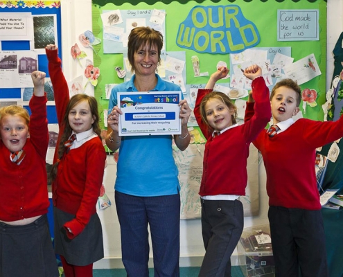 Cheering schoolchildren and Waste Educator Sally holding a certificate
